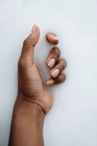 Dark skin hand in the milky smooth water substance