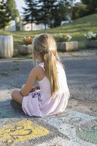 Girl sitting on footpath