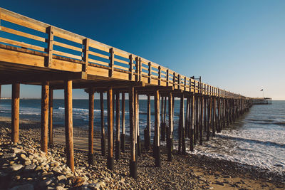 Pier on beach against clear sky