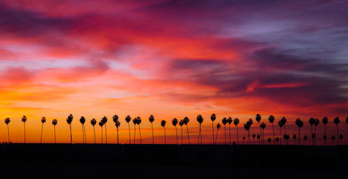 Silhouette people against dramatic sky during sunset