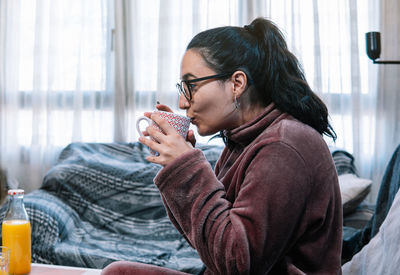 Side view of young woman drinking beer in cafe