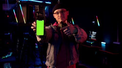 Portrait of man using mobile phone while sitting in darkroom