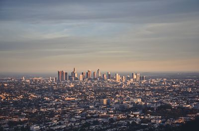 Aerial view of city buildings against cloudy sky