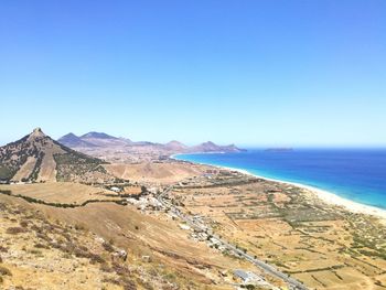 Scenic view of sea and mountains against clear blue sky