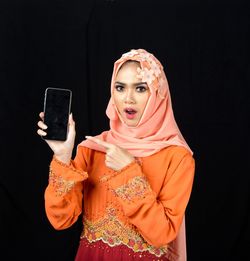 Midsection of man using smart phone against black background