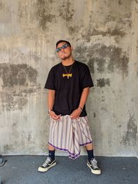 Portrait of young man standing against wall