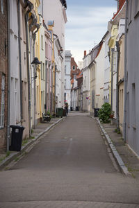 Empty road amidst buildings in city