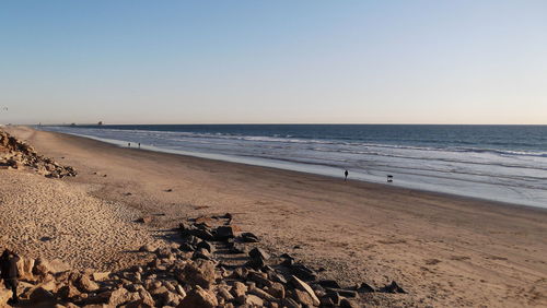 Scenic view of beach against clear sky during sunset