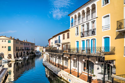 Canal amidst buildings in city against sky