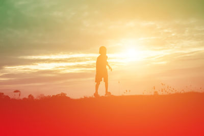 Silhouette person standing on field against sky during sunset