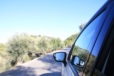 Reflection of car on side-view mirror against clear sky
