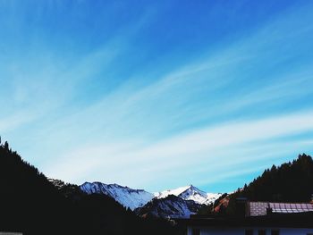 Scenic view of snow covered mountains against blue sky