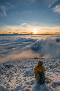 Rear view of man on snow against sky during sunset