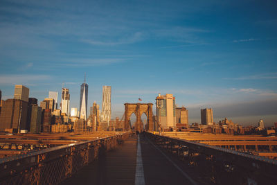 Brooklyn bridge in city against blue sky