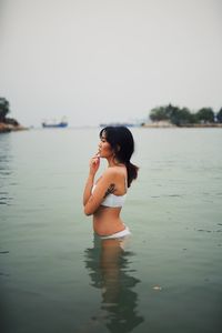 Woman standing in sea against sky