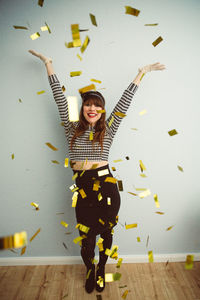 Portrait of smiling young woman standing against wall