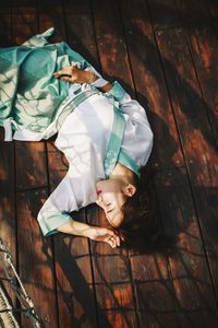 High angle view of woman lying down on wooden floor