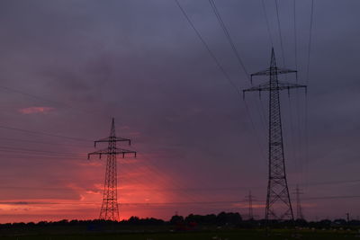 Low angle view of electricity pylon against sky during sunset