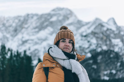 Portrait of woman wearing warm winter clothes, standing under mountains in julian alps