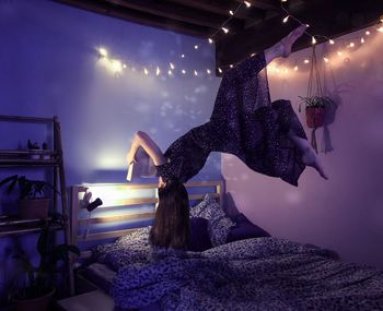 Woman standing by illuminated lights on table against sky at night