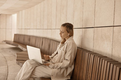 Businesswoman using laptop sitting on bench