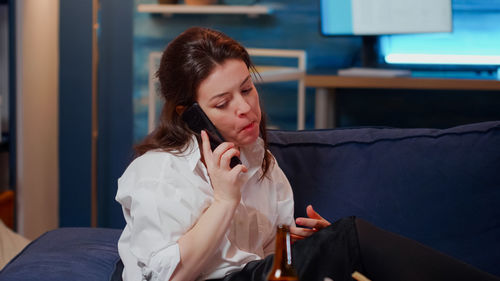 Young woman using mobile phone while sitting at home