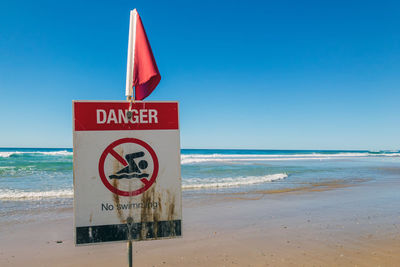 Information sign on beach against clear sky