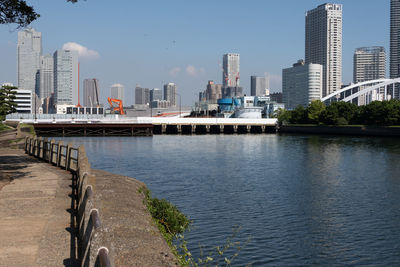 Bridge over river by buildings in city against sky