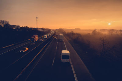 Cars on road against sky during sunset