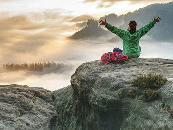 Girl backpacker sitting on top of the mountain and enjoying new born of the day. fall season hike.