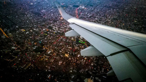 High angle view of airplane flying over buildings in city