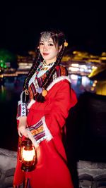 Portrait of smiling young woman standing against wall