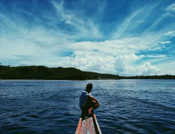 Rear view of man standing in river against sky