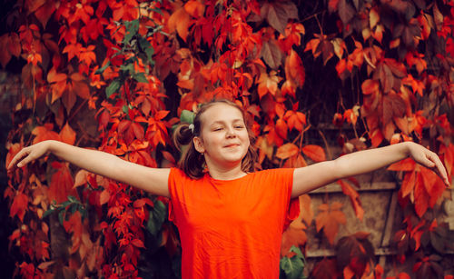 Low angle view of girl standing by leaves during autumn