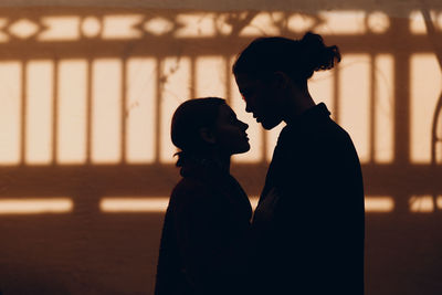 Silhouette couple standing against blurred background at sunset