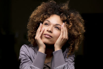 Portrait of daydreaming woman in front of black background