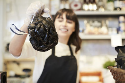 Smiling female owner holding mussels in store