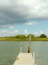 Pier on lake against cloudy sky