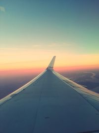 Close-up of cropped airplane against sky at sunset