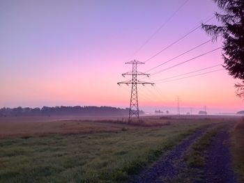 Electricity pylon on field against sky during sunset