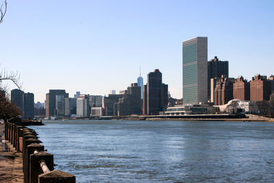 Modern buildings by river against sky in city