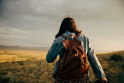 Rear view of woman standing on field against sky