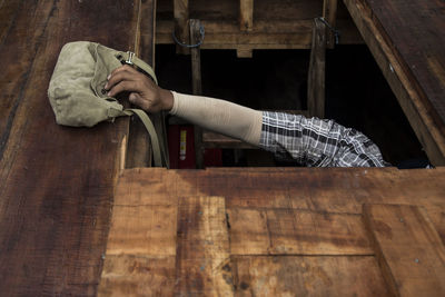 Cropped image of man by shoulder bag on wooden floor