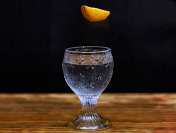 Close-up of wineglass on table against black background