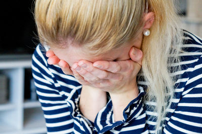 Close-up of depressed woman covering face with hands at home