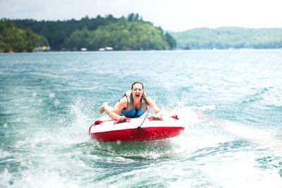 Young woman on inflatable raft pulled by speedboat in lake blue ridge