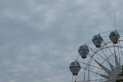 Low angle view of ferris wheel against cloudy sky