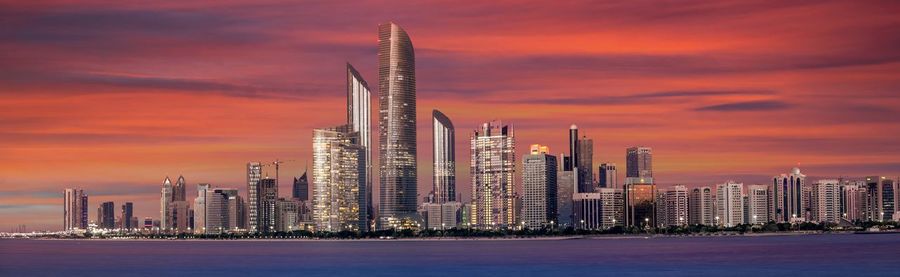 Modern buildings against sky during sunset