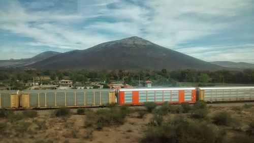 House against mountain range against cloudy sky