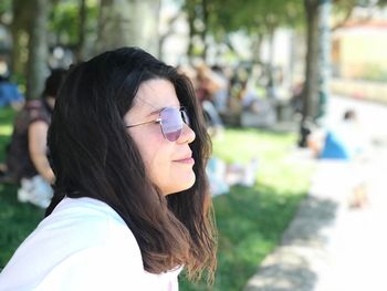 Side view of young woman wearing sunglasses looking away in park